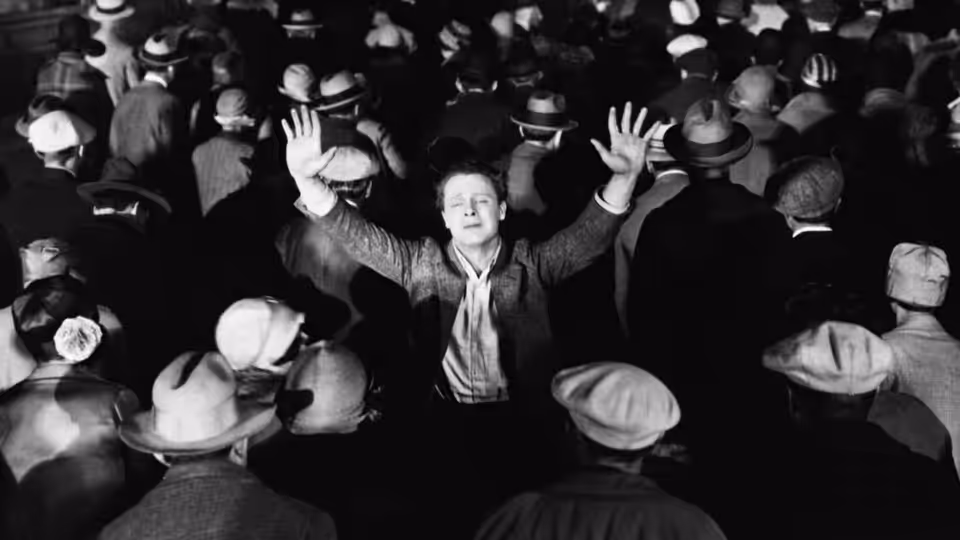 John 'Johnny' Sims (James Murray) raises his hands above a crowd