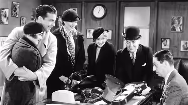 A group gathers around a table of hats as a man examines merchandise