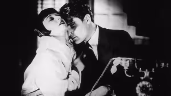 Alwa Schön (Francis Lederer) leans close to Lulu (Louise Brooks) beside a telephone