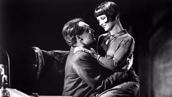 Dr. Ludwig Schön (Fritz Kortner) sits with Lulu (Louise Brooks) on his lap