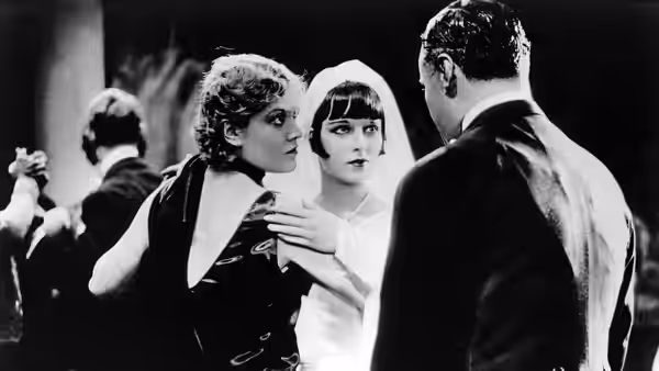 Lulu (Louise Brooks) stands between a woman and a man in formal dress
