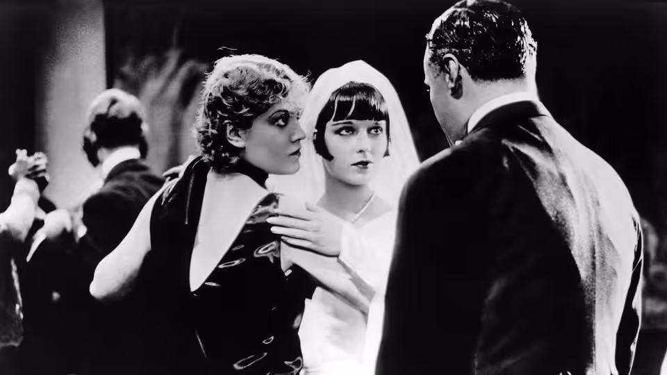 Lulu (Louise Brooks) stands between a woman and a man in formal dress