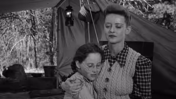 Charlotte (Bette Davis) embraces Tina beneath a tent at the cabin