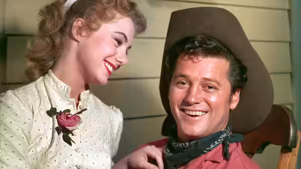 Laurey Williams (Shirley Jones) smiles beside Curly McLain (Gordon MacRae) in his cowboy hat