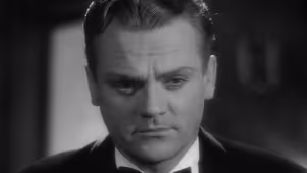 A stern, clean-cut man in a suit looks straight ahead