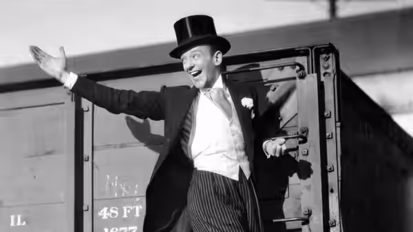 Lucky Garnett (Fred Astaire), wearing a top hat, gestures beside a train carriage
