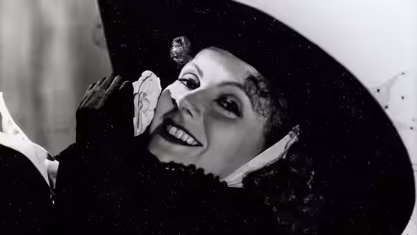 Marguerite Gautier (Greta Garbo) smiles beneath a dark veil