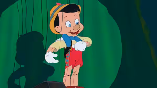 Pinocchio suspended by strings against a green curtain