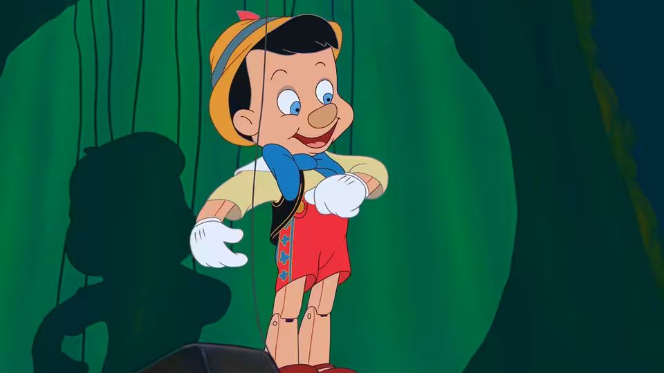 Pinocchio suspended by strings against a green curtain