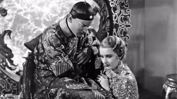 General Yen (Nils Asther) leans over Megan Davis (Barbara Stanwyck) beside an ornate screen