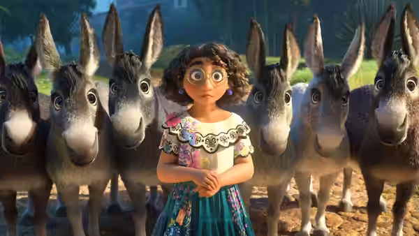 Mirabel standing among donkeys on a dirt path outdoors