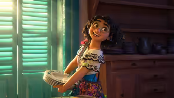 Mirabel carrying plates in a bright kitchen with wooden cabinets