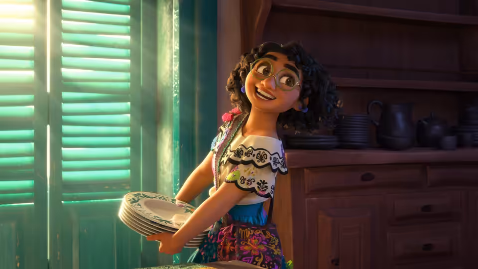 Mirabel carrying plates in a bright kitchen with wooden cabinets
