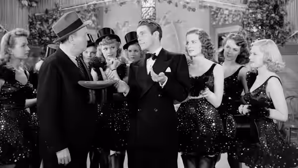 A formally dressed man gestures among party guests in evening clothes