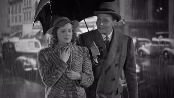 A woman and a man walk beneath an umbrella on a city street