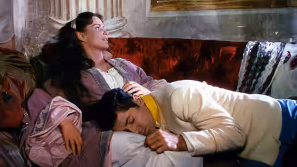 A woman reclines on a sofa as a man in white rests against her lap