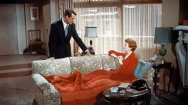 Nickie Ferrante (Cary Grant) stands beside Terry McKay (Deborah Kerr) resting on a sofa