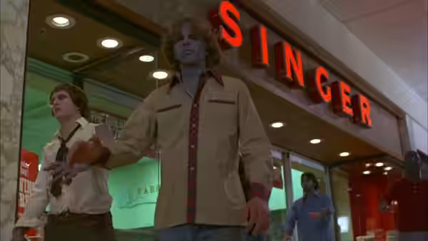 Two zombies stand in front of a red Singer store sign