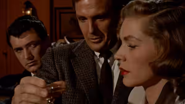 Kyle Hadley (Robert Stack) and Mitch Wayne (Rock Hudson) watch Lucy Moore Hadley (Lauren Bacall) hold a glass