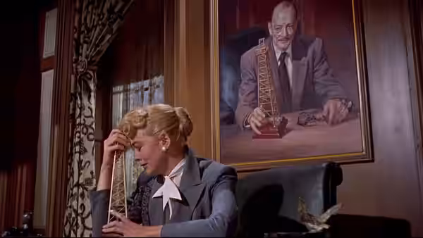 Marylee Hadley (Dorothy Malone) sits with her head bowed beneath a portrait of her father
