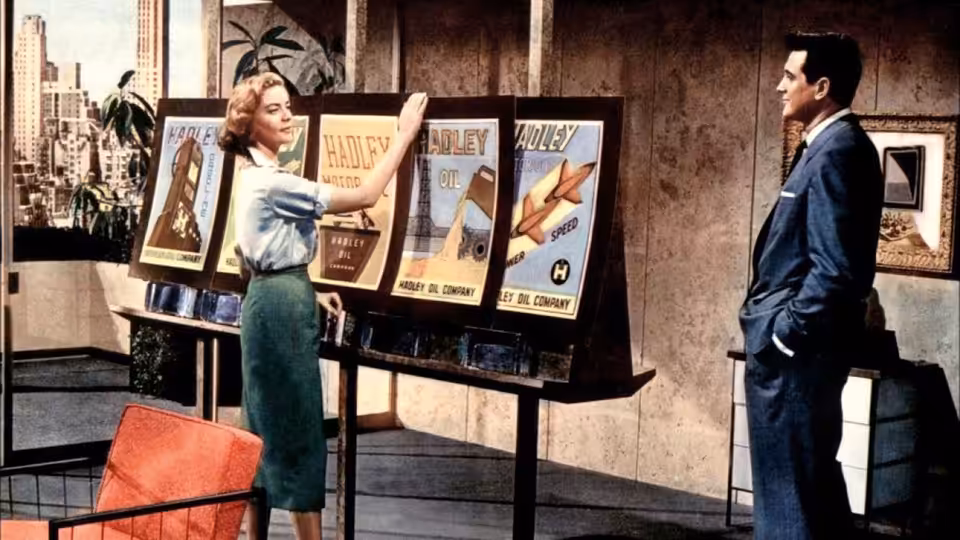 A woman presents display boards to a suited man in an office