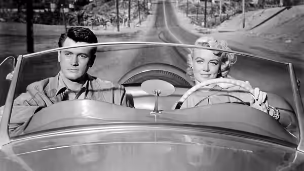 Mitch Wayne (Rock Hudson) rides beside Marylee Hadley (Dorothy Malone) in a convertible