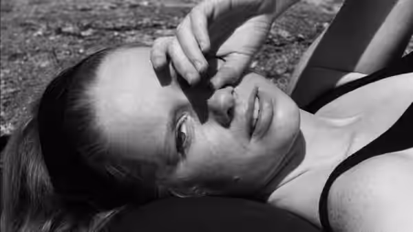 A woman lies back with a hand resting across her face