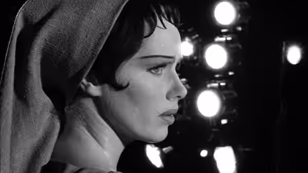 A woman in a hood looks toward bright lights