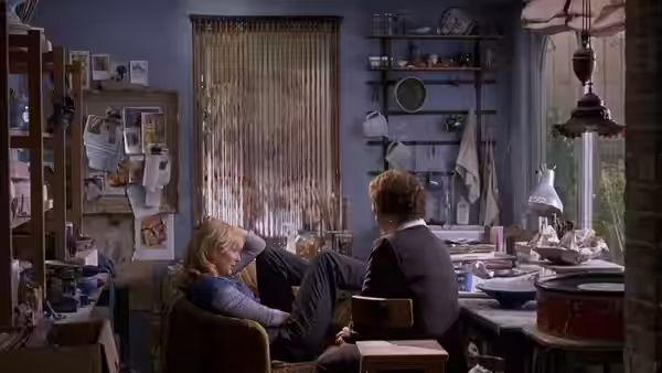 Sheba Hart (Cate Blanchett) sits with Steven Connolly (Andrew Simpson) in a cluttered room