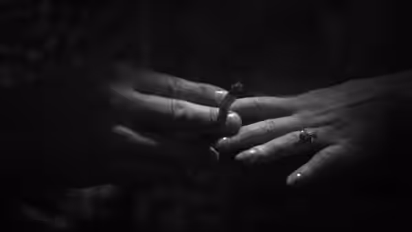 A hand wearing a ring rests across another hand