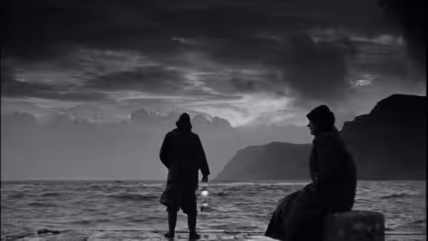 Two figures wait beside the sea beneath a dark, clouded sky