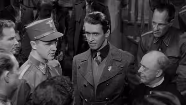 Martin Breitner stands among uniformed men and Professor Victor Roth in a crowded hall