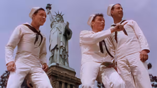 Three sailors look up at the Statue of Liberty