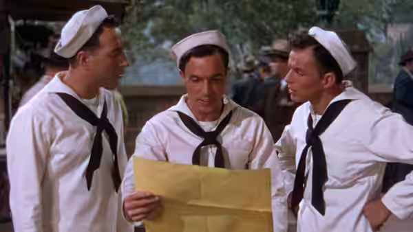 Three sailors gather around a folded map on a city street