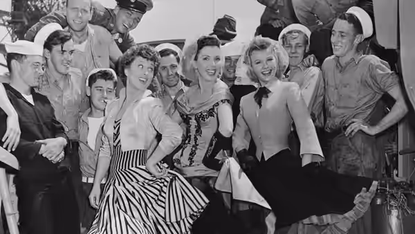 Sailors and women pose together in a crowded dance hall