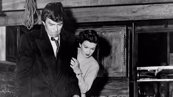 Martin Donnelly (James Mason) stands with Lucia Harper (Joan Bennett) in a room