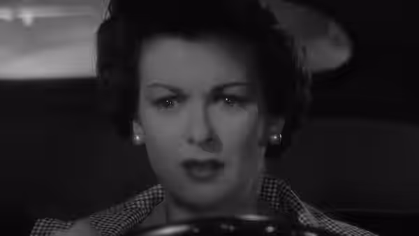 Lucia Harper (Joan Bennett) looks ahead from inside a car