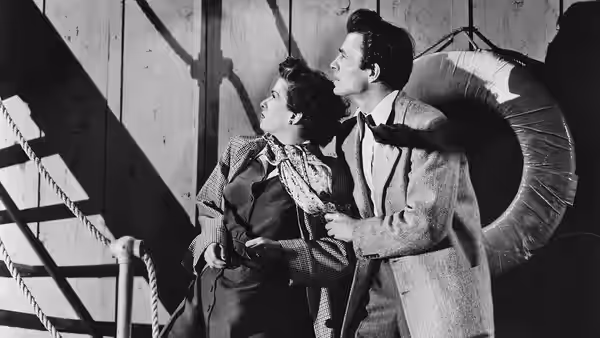 Martin Donnelly (James Mason) and Lucia Harper (Joan Bennett) look upward beside a staircase