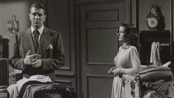 Mark Lamphere (Michael Redgrave) stands beside a bed as Celia Lamphere (Joan Bennett) watches