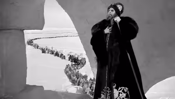 Ivan stands by a window overlooking a procession winding through the snowy landscape