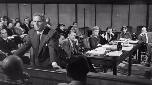 Adam Bonner (Spencer Tracy) leans on the courtroom rail before the judge and jury