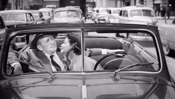 Adam Bonner (Spencer Tracy) reclines in a parked car as a woman leans toward him