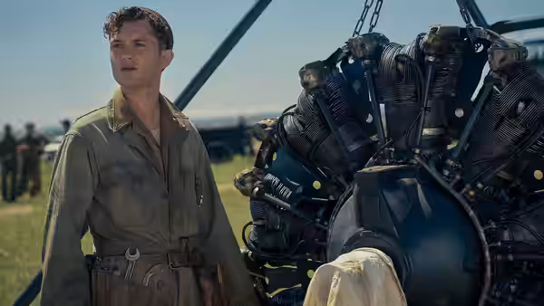 An airman stands beside a bomber engine on the airfield