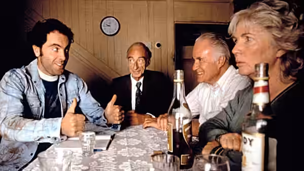Pig Finn (James Nesbitt) talks with villagers gathered around a kitchen table