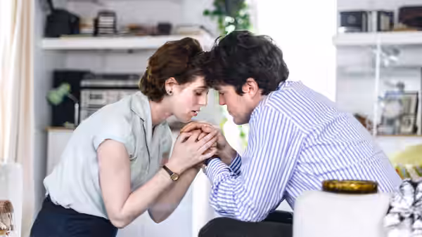 Julie (Honor Swinton Byrne) and Anthony (Tom Burke) touching foreheads while holding hands