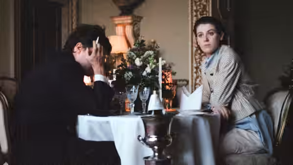 Anthony (Tom Burke) and a woman seated at a formal dinner table