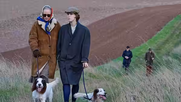 Rosalind (Tilda Swinton) and Anthony (Tom Burke) walking dogs across a field