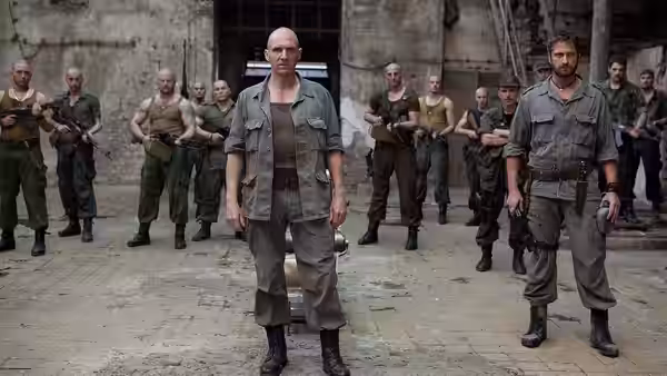 Coriolanus (Ralph Fiennes) stands with armed soldiers in a ruined hall, Aufidius (Gerard Butler) beside him