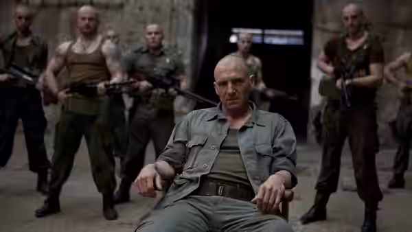 Coriolanus (Ralph Fiennes) sits bound in a chair surrounded by armed men
