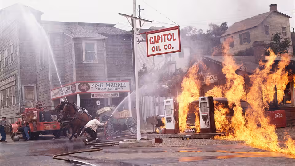 Flames engulf a roadside building beside the Capitol Oil sign and a parked truck